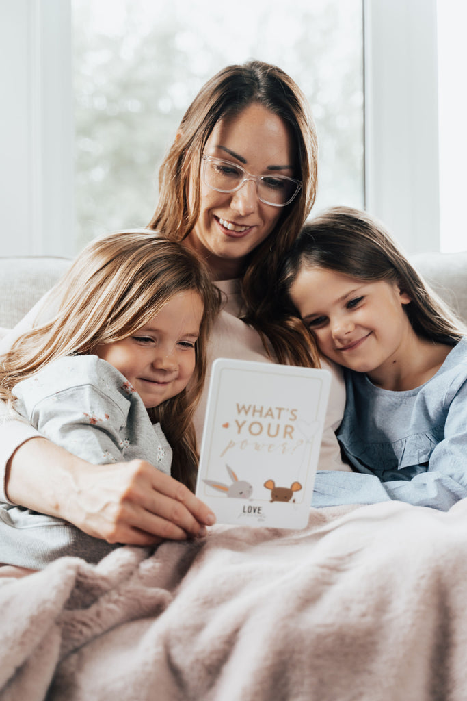Mother sitting with two daughters reading an affirmation card